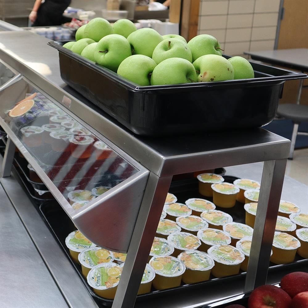 Apples and juice displayed in a school cafeteria line